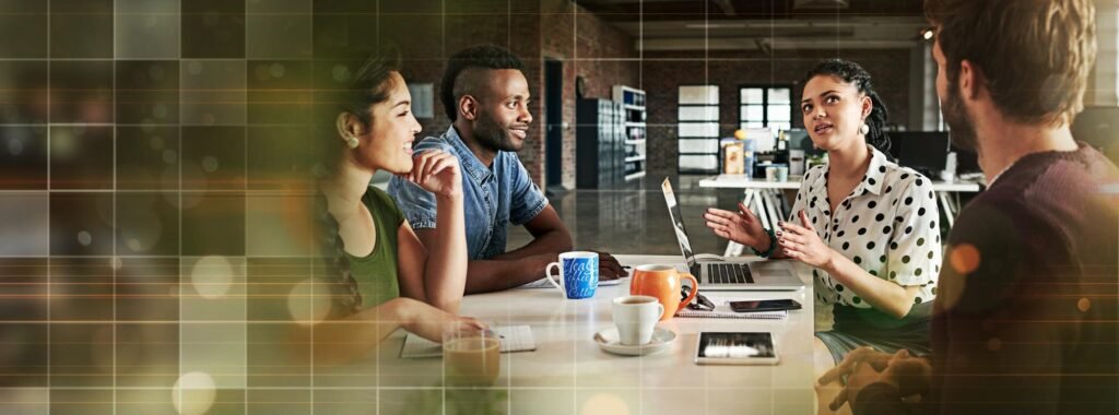 Group of diverse professionals collaborating at a table with laptops and coffee, discussing strategies for enhancing Google Business Profiles and local SEO engagement.
