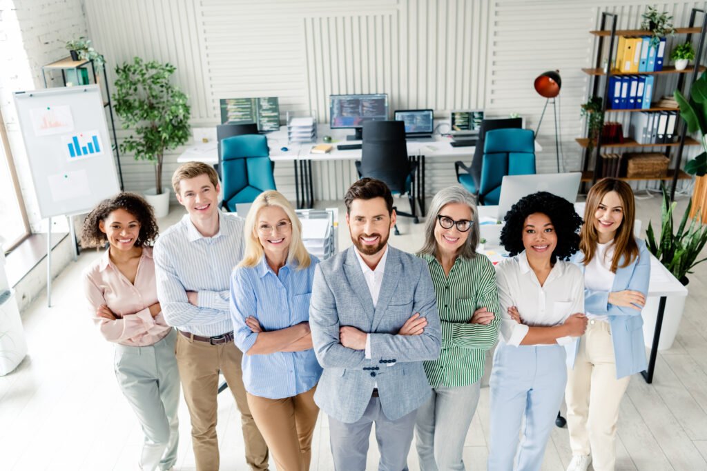 Team of diverse professionals smiling confidently in a modern office setting, symbolising collaboration and engagement for enhancing Google Business Profiles and local SEO.