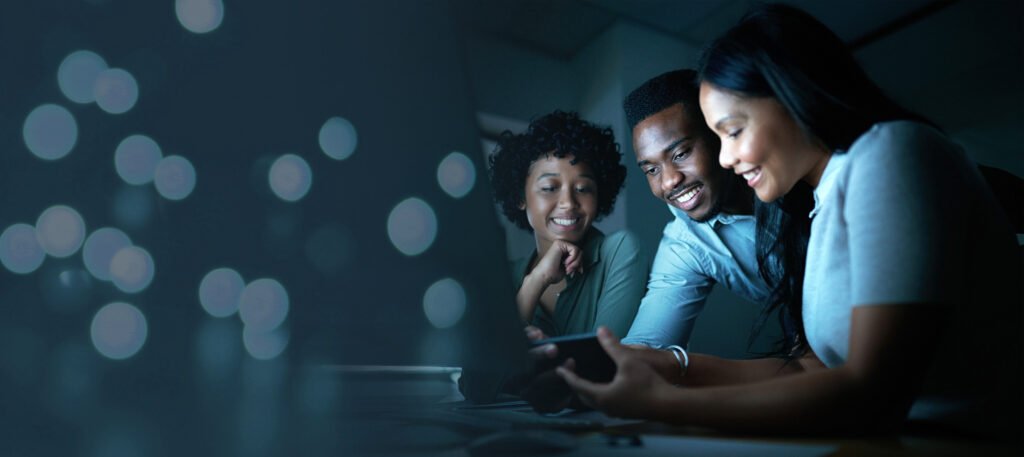Three diverse individuals engaged in a collaborative discussion while viewing content on a smartphone, with a blurred background featuring soft, glowing lights, illustrating the theme of enhancing customer engagement through video content.