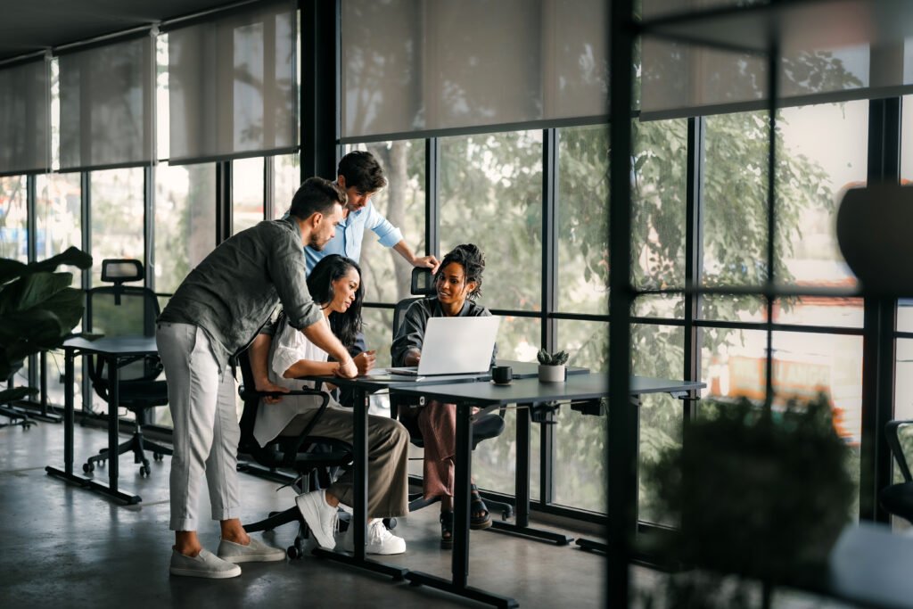 Group collaborating in a modern office, discussing Google Business Profile strategies, with a laptop displaying digital marketing tools and a focus on local SEO enhancement.
