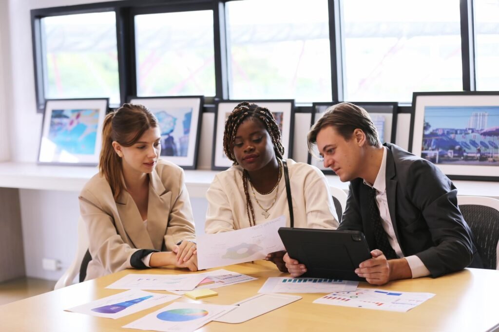 Three professionals collaborating at a table with graphs and reports, discussing local SEO strategies and digital marketing insights for business growth.