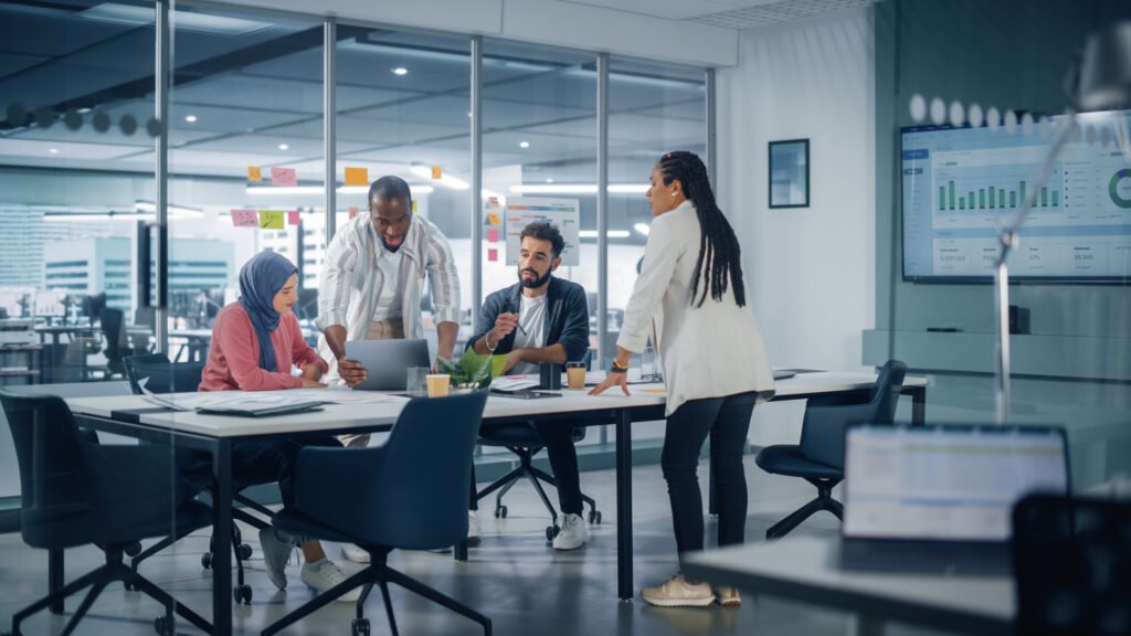 Group of diverse professionals collaborating around a conference table, discussing strategies for enhancing local search visibility and citation management, with charts displayed on a screen in a modern office setting.