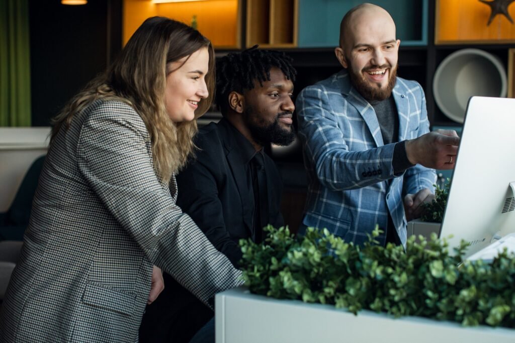 Three professionals collaborating at a computer, discussing video content strategies to enhance Google Business Profiles and customer engagement, with greenery in the foreground.