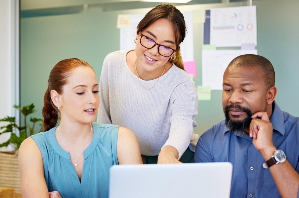 Three professionals collaborating around a laptop, discussing strategies for optimising Google Business Profile management and enhancing local SEO.