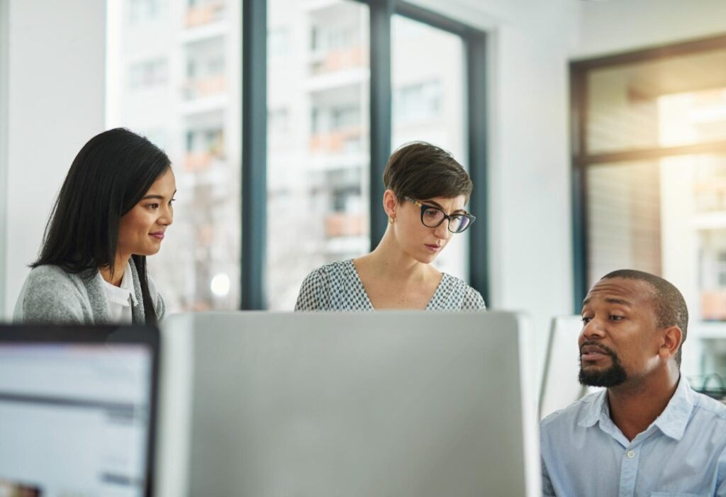 Three professionals engaged in a collaborative discussion in a modern office, focusing on strategies for managing Google Business Profiles and enhancing local SEO visibility.